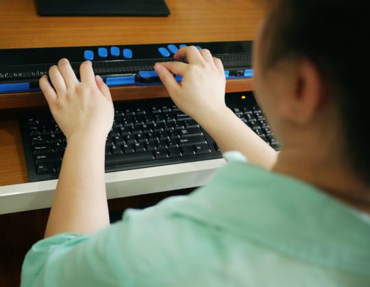 woman using special keyboard for visually impaired