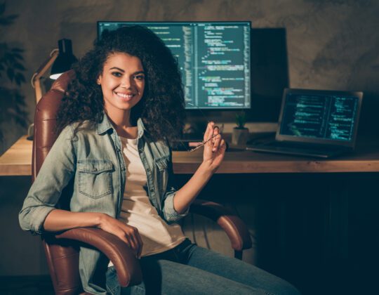 Female Software Engineer sitting at her desk reviewing code from her team