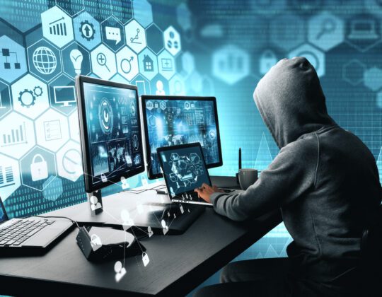 Side view of ethical hacker using computer with digital interface while sitting at desk of blurry interior.