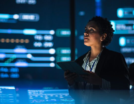 Female cybersecurity professional working in front of data screens