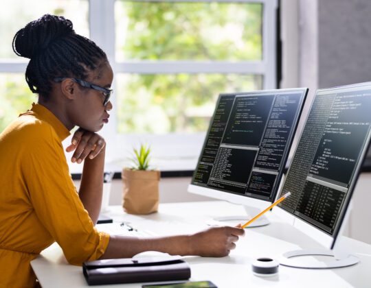 African American female software developer writing code on computer
